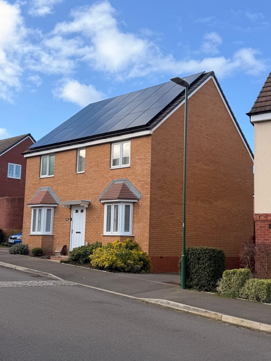 A modern brick semi with an all-black array running the full width of the roof slope.