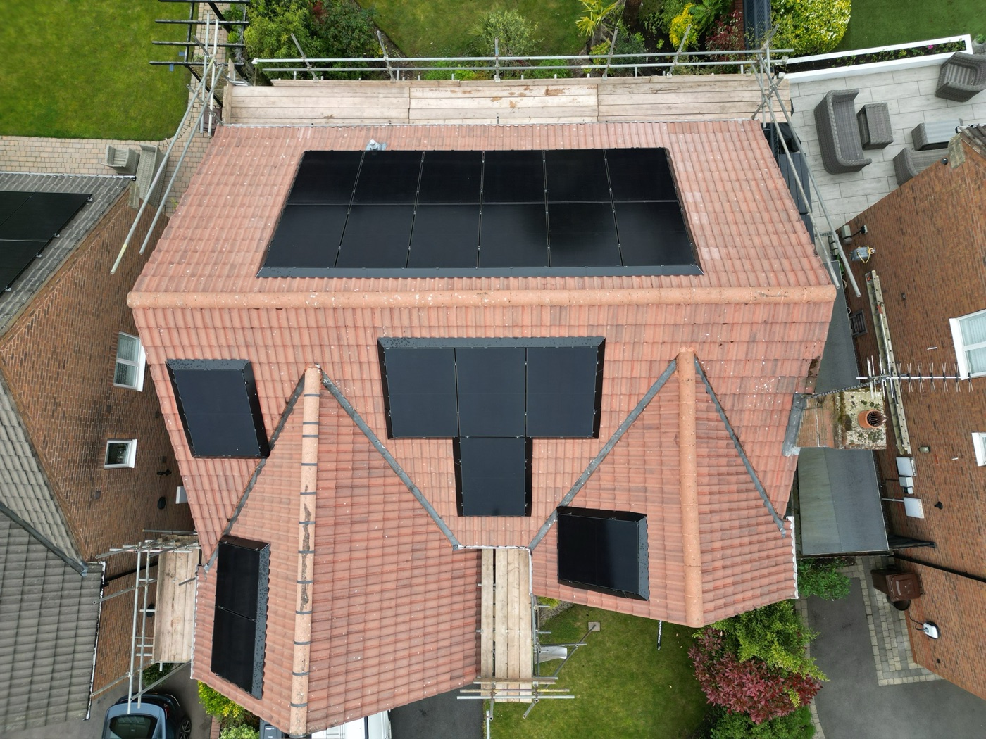 A large detached house with panels across four separate roof aspects, seen from above.