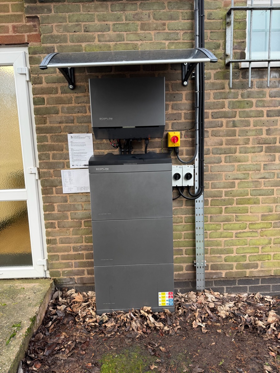 An EcoFlow PowerOcean battery and inverter mounted outside on a brick wall under a weather hood.