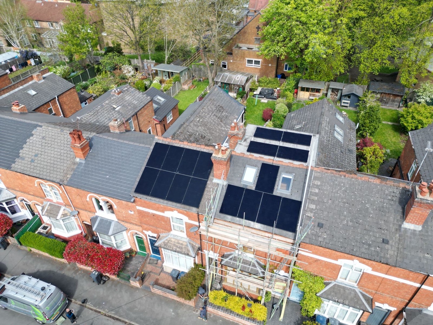 Arrays on the rear roofs of a Birmingham terrace, scaffold still up and the van on the street below.