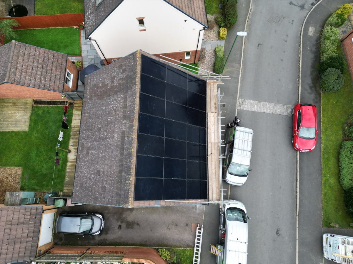 An in-progress array on a terraced roof with the installation vans parked at the kerb.